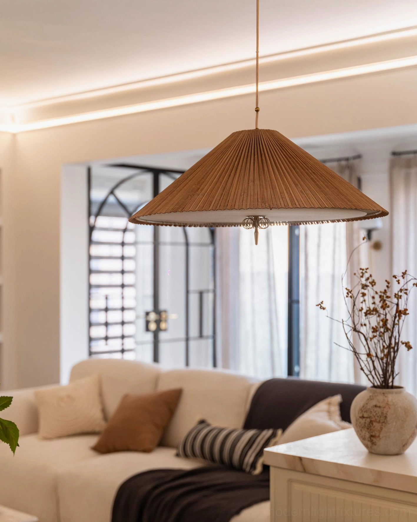 Handwoven bamboo pendant with warm glow illuminating side view of pleated shade geometry