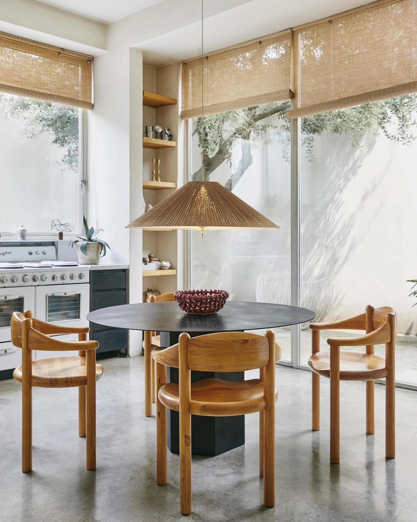 Pleated bamboo pendant lamp in modern sunlit kitchen dining area with light wood furniture