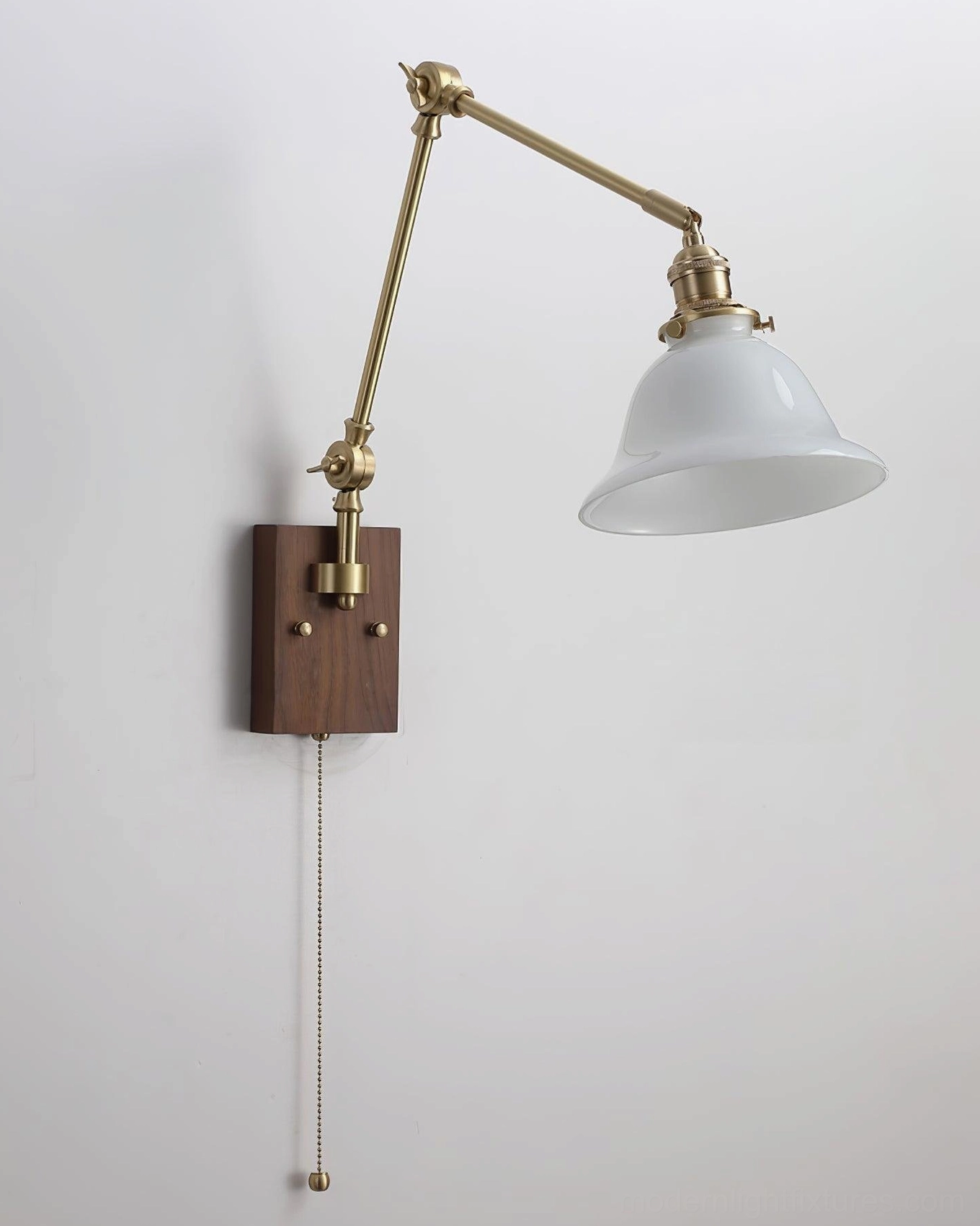 Banker swing arm wall sconce with white glass dome shade and brass metal arms on plain white wall, front flat view showing pull chain switch