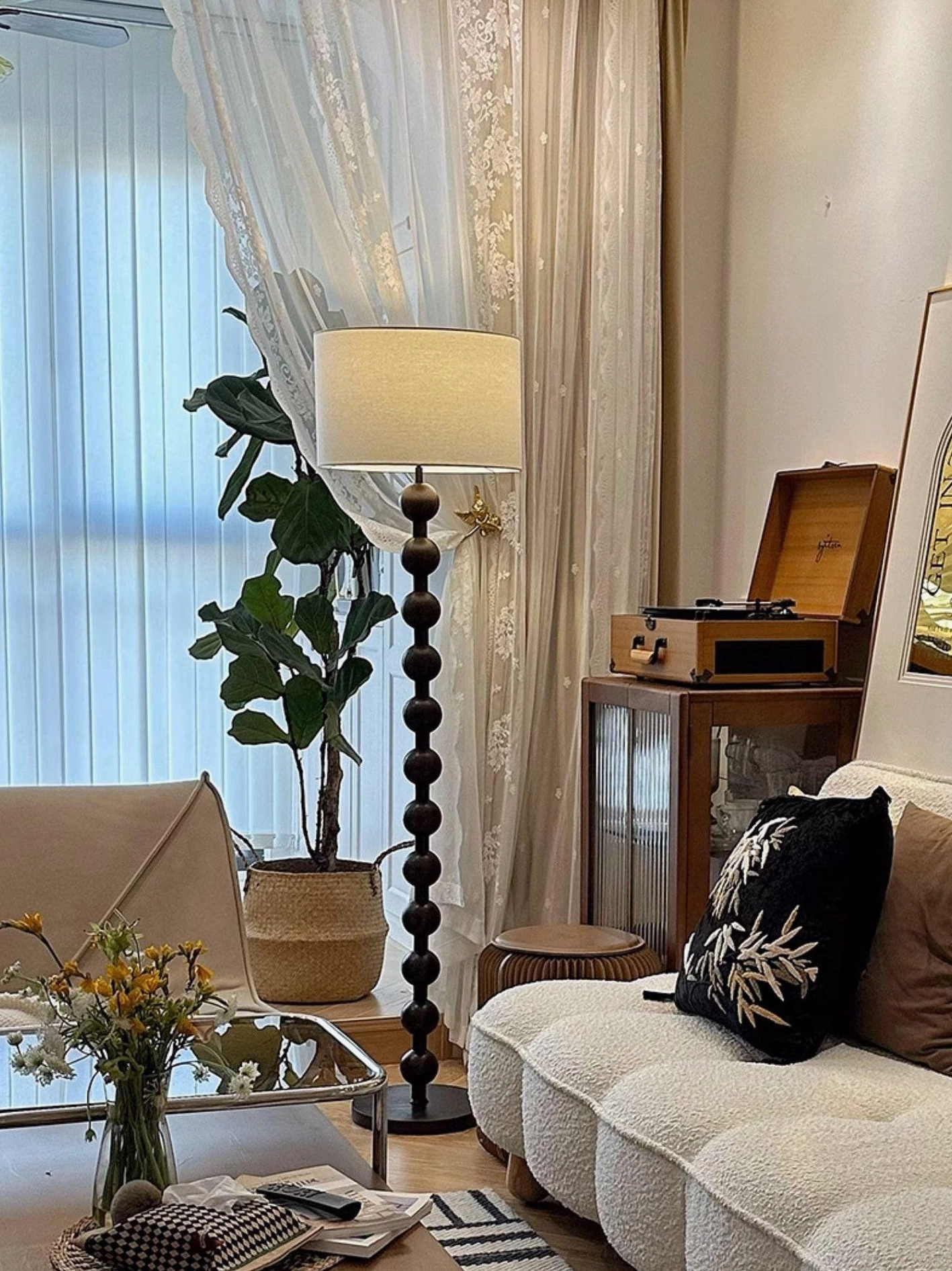 Natural wood barbell floor lamp beside geometric area rug and potted plant