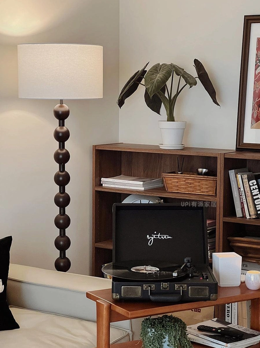 Natural wood barbell floor lamp providing ambient lighting in reading nook