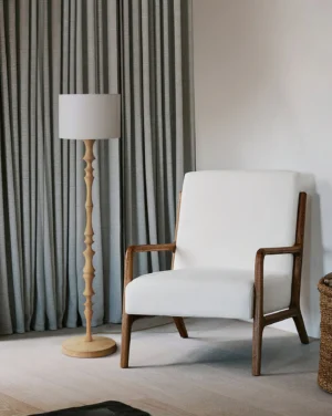 Natural wood Bastino floor lamp with cylindrical fabric shade in contemporary living room setting