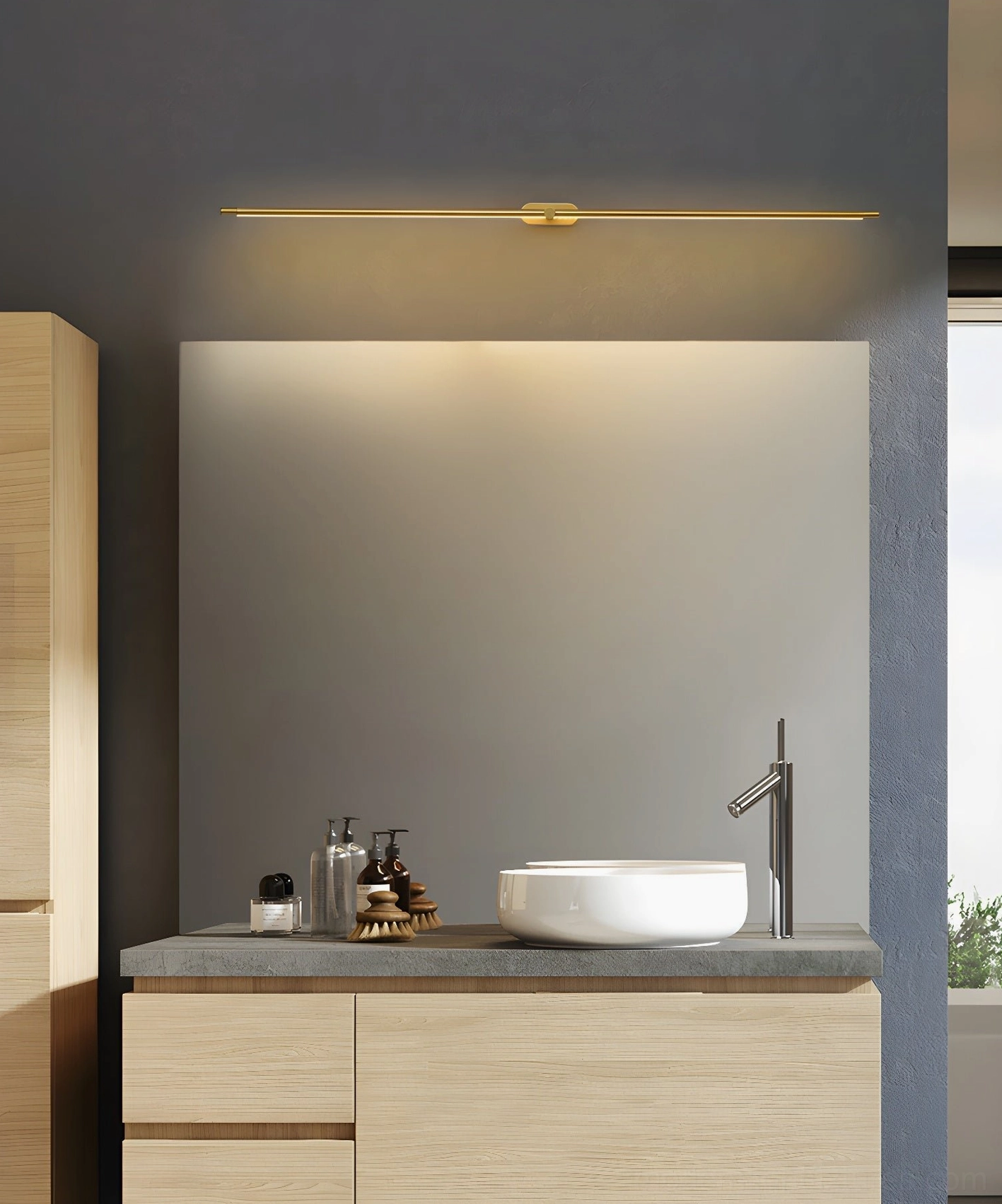 Brass gold linear wall lamp above bathroom vanity providing even edge-to-edge illumination for modern bath space