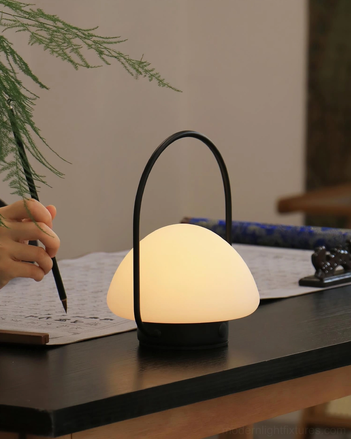 Battery-powered portable table lamp with frosted glass shade on home office workspace desk, traditional workspace setting