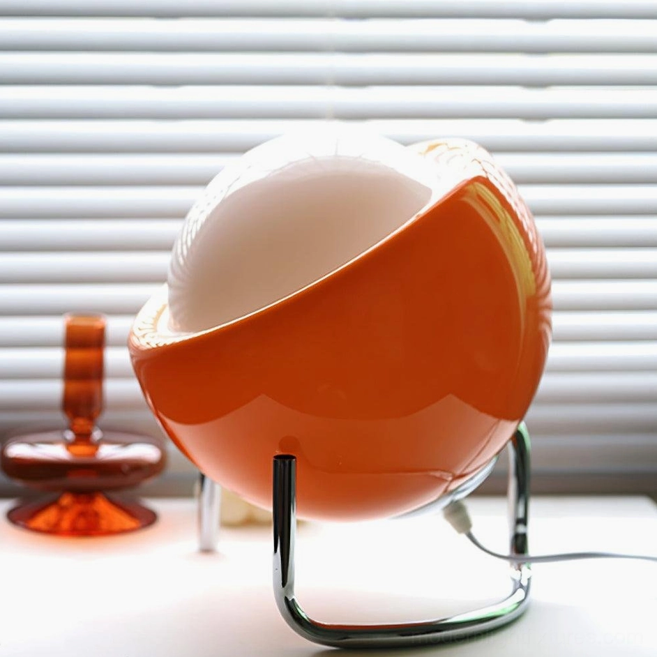 Large Bauhaus sphere table lamp with orange glass dome and curved chrome stand, low angle view on office desk