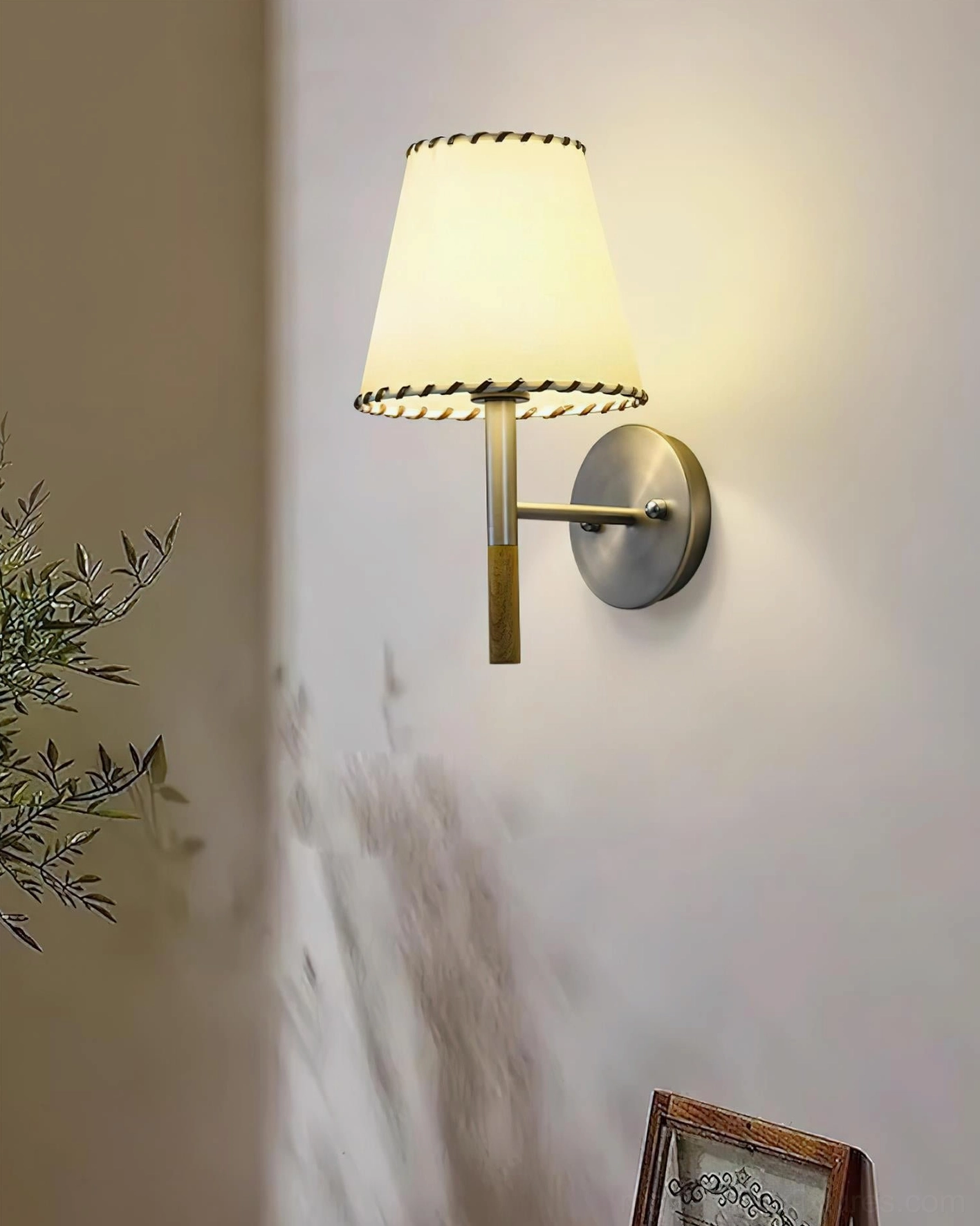 BC2 wall sconce installed on gray wall in cozy residential corner with warm minimalist decor and plant