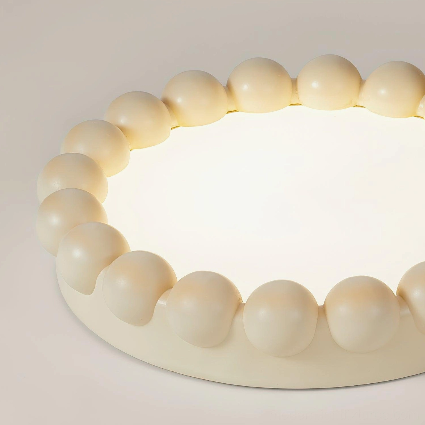 Studio close-up of beaded ceiling light showing circular light panel and smooth round bead craftsmanship
