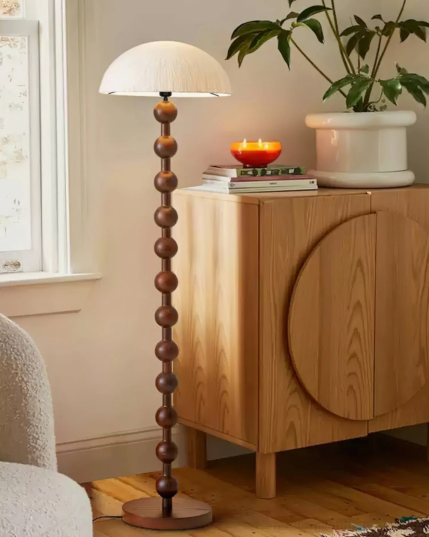 Dark walnut beaded floor lamp in sunlit entryway nook beside wooden cabinet
