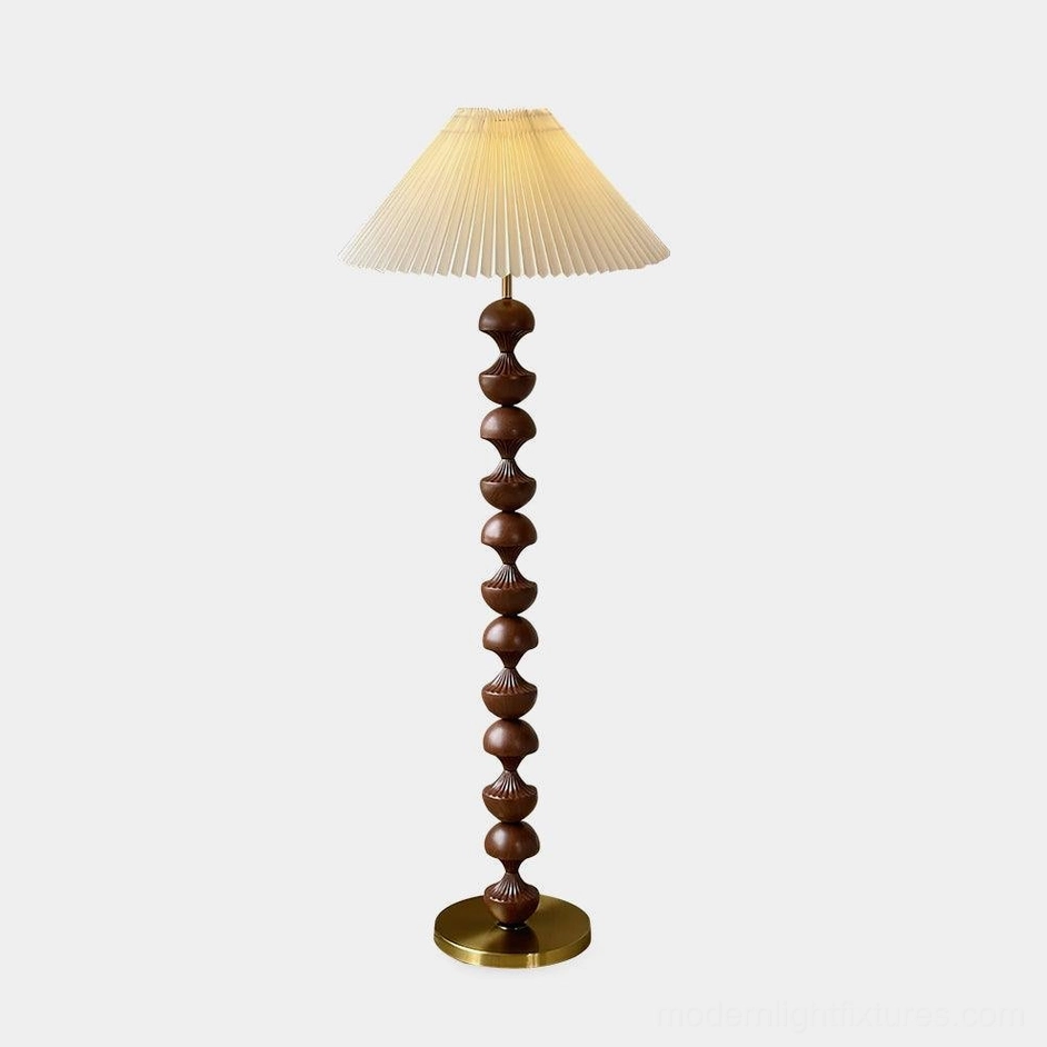 Beaded wood floor lamp with pleated cream shade and brass metal base, front view showcasing dark brown stacked wood pole and sculptural column design