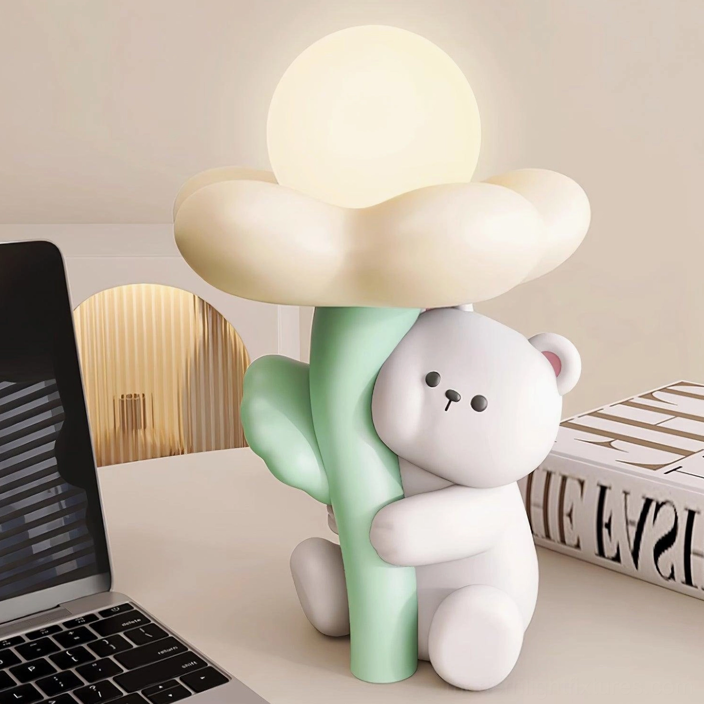 Close-up three-quarter view of cute bear lamp on workstation desk with laptop and fashion books nearby