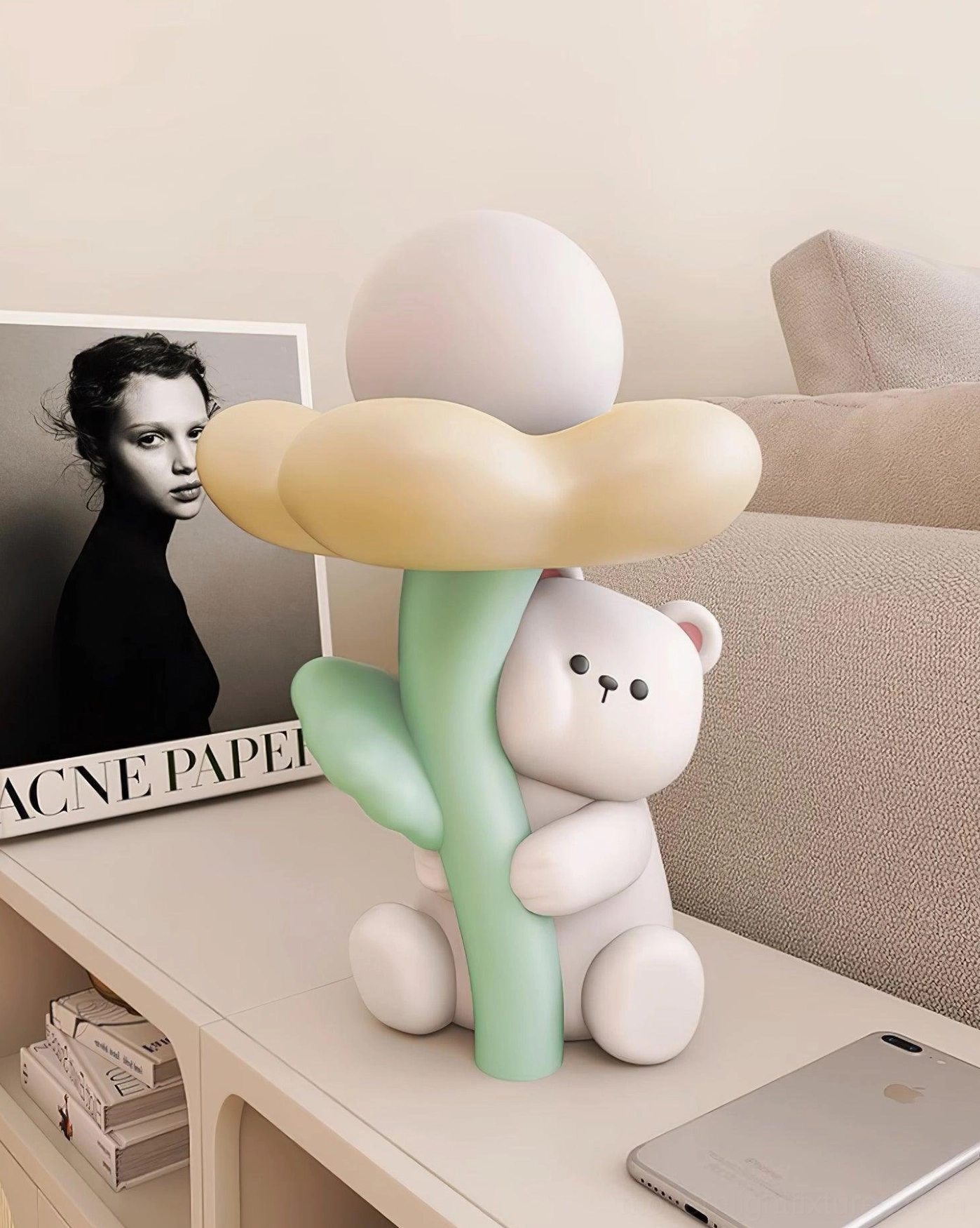 Bear-shaped nightlight lamp in living room side table scene with portrait print, smartphone and stacked books creating ambient lighting