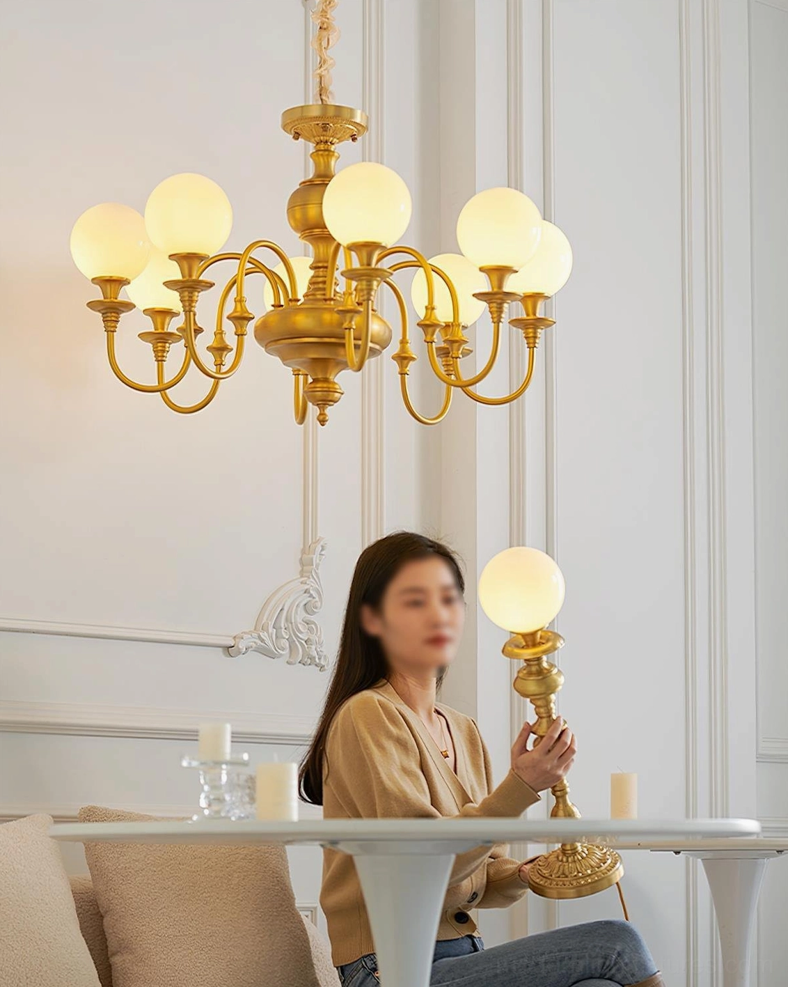 Beatty brass chandelier and table lamp in French countryside dining area, side view with illuminated frosted glass shades