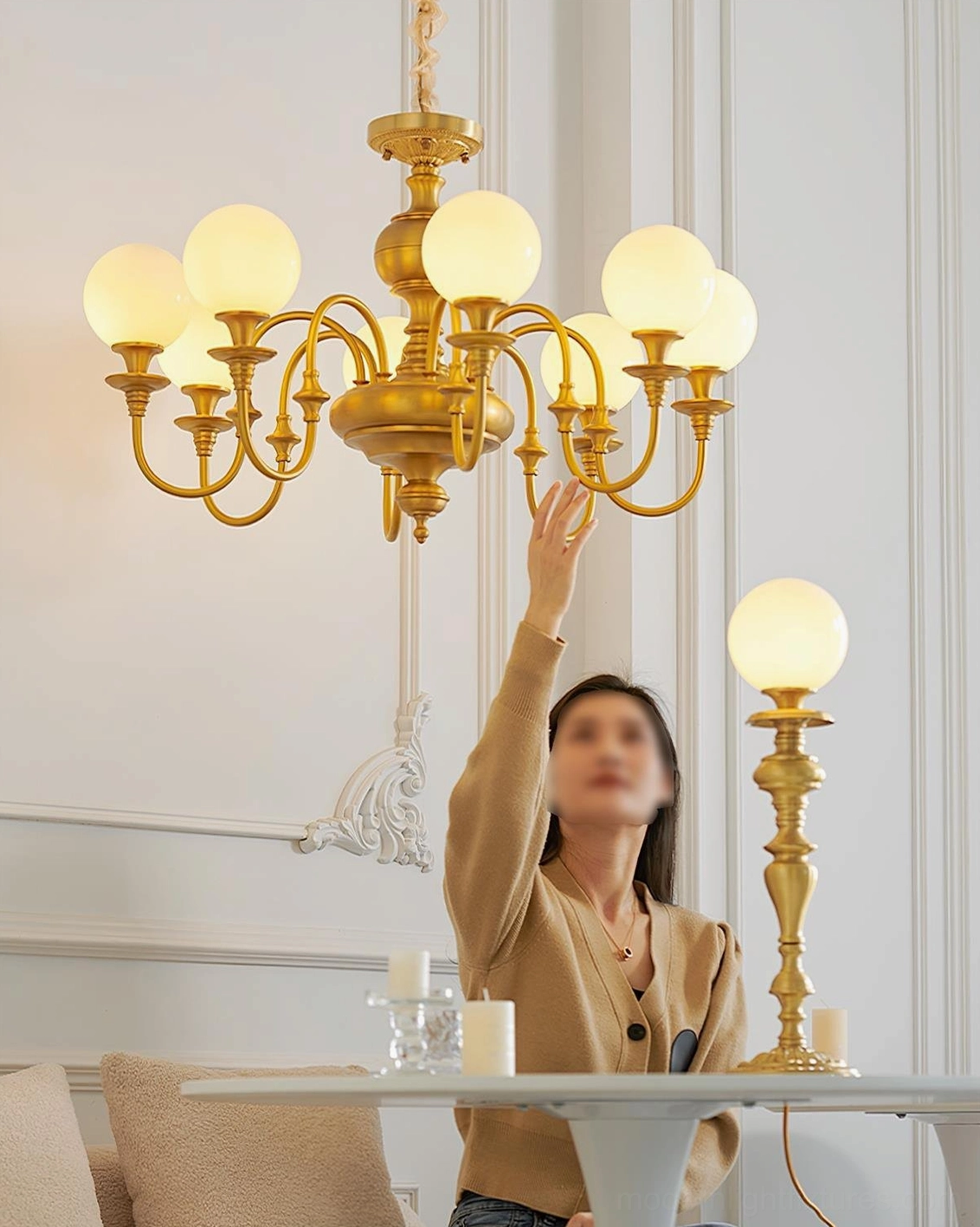 Beatty brass multi-head chandelier and table lamp glowing in French home dining space, low indoor eye-level perspective