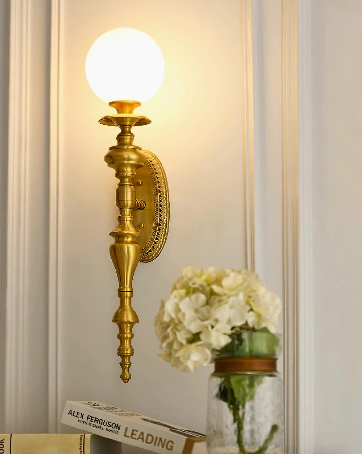 Brass wall sconce creating warm ambient lighting in Art Deco inspired interior with decorative accents