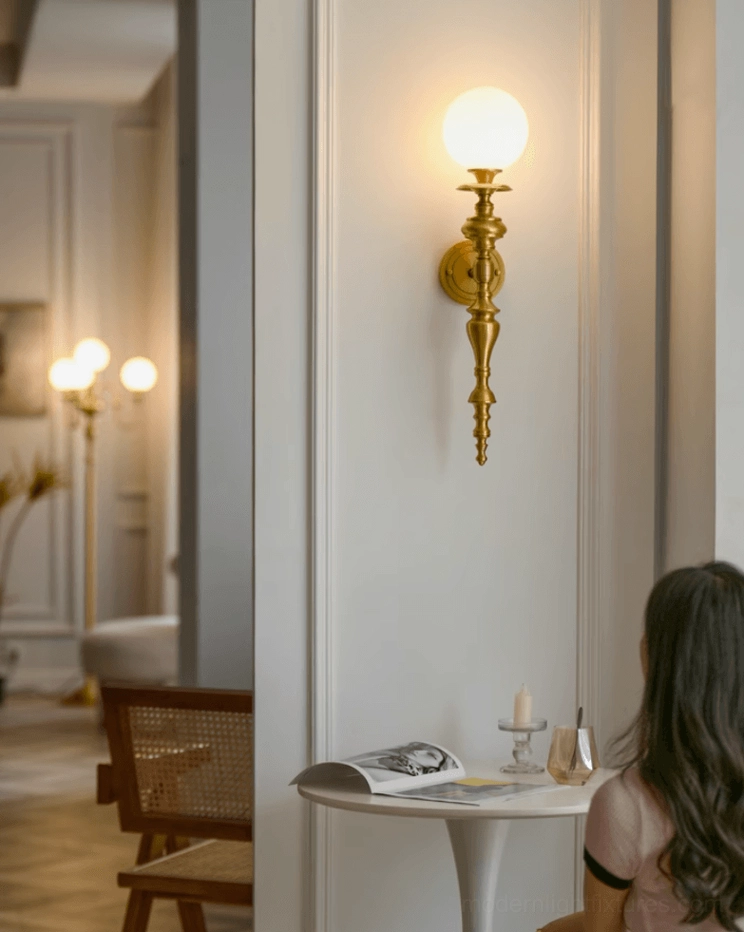 Beatty brass wall sconce in luxury dining space creating warm vintage gold ambient lighting