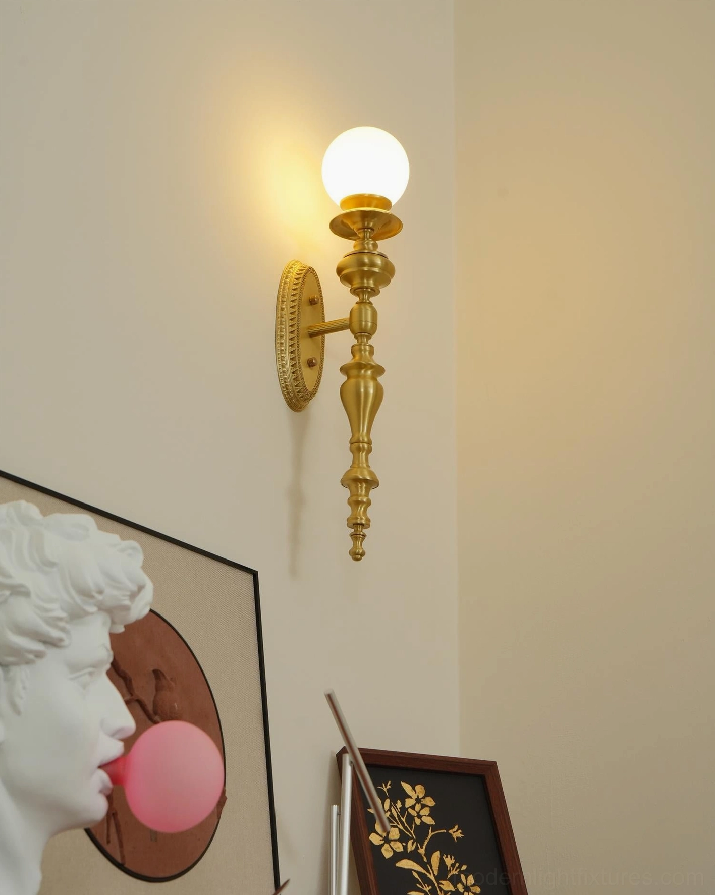 Wall mounted brass sconce with warm gold finish illuminating entryway architectural feature