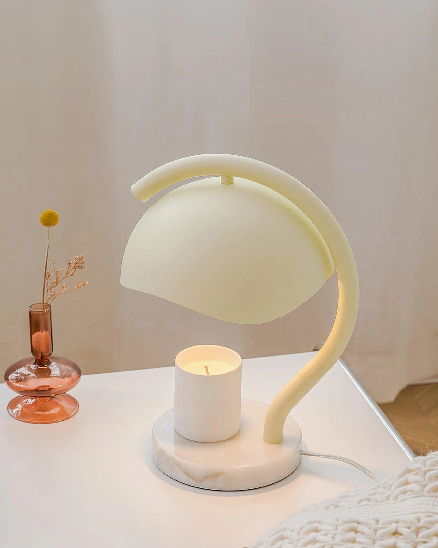 Elegant candle warmer lamp on white bedside table with dried flower decoration and warm white ambient lighting
