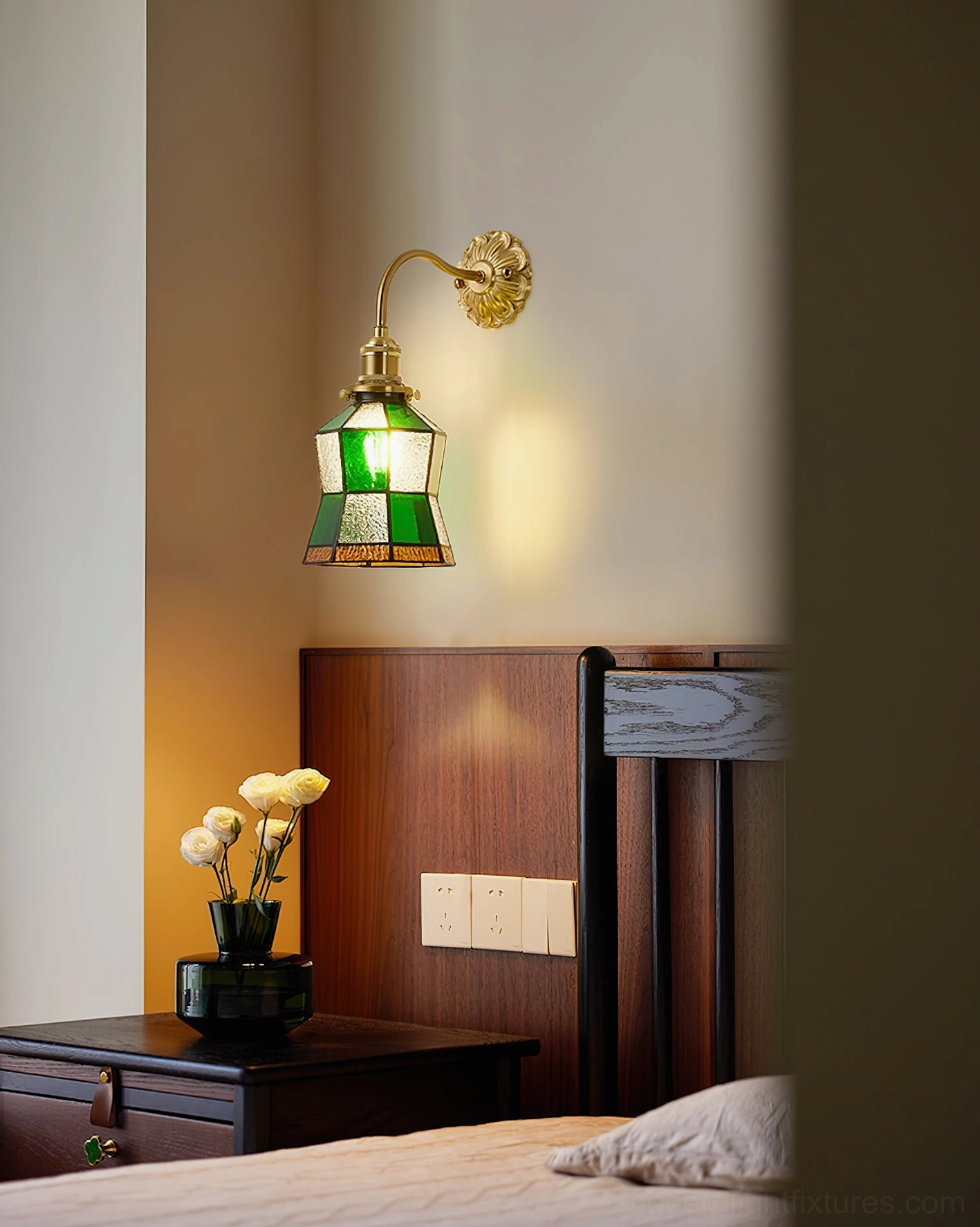 Vintage stained glass wall sconce mounted above bedroom nightstand in cozy bedroom setting, creating warm jeweled ambient light