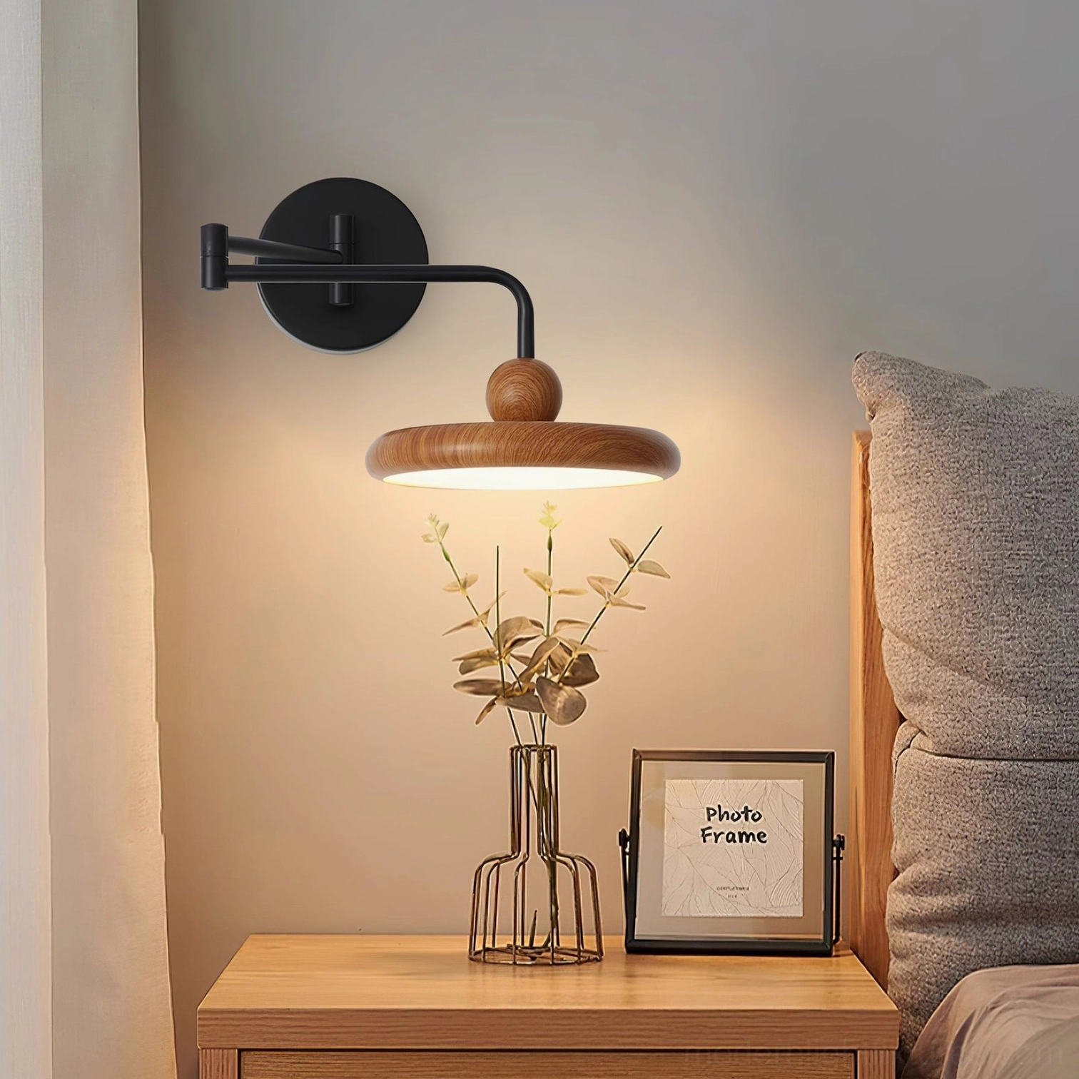 Warm ambient wall sconce installed in bedroom creating cozy lighting atmosphere beside bedside table with decor