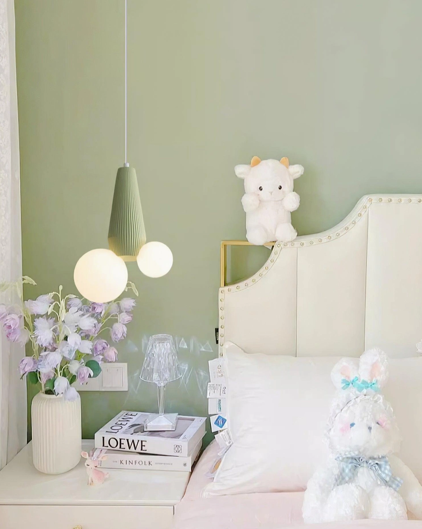 Contemporary pendant lamp with sage green base and asymmetrical frosted white glass shades on bedside table