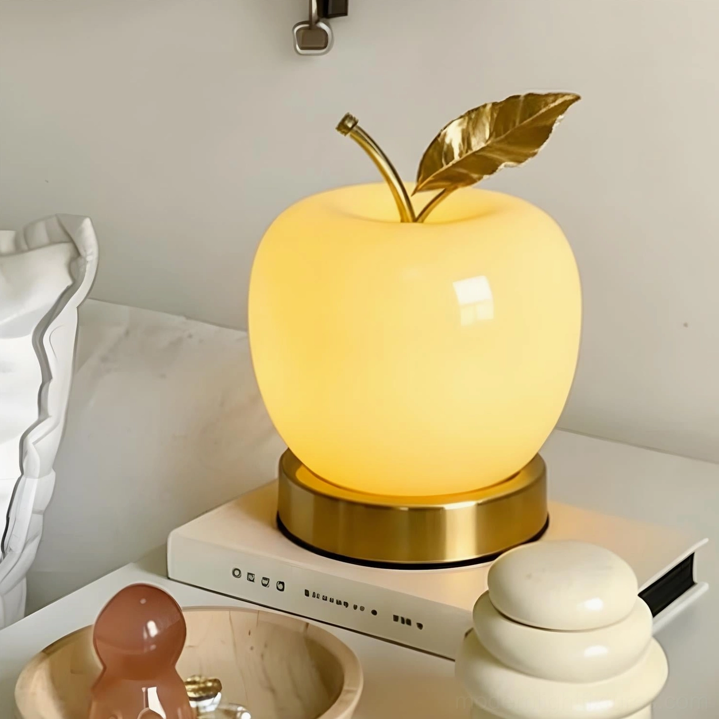 Yellow beige apple lamp glowing warm light from bedroom setup, matte finish with gold base illuminated