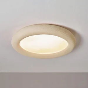 Beige matte finish round flush mount ceiling light installed on two-tone interior wall with warm ambient lighting and modern minimal frame