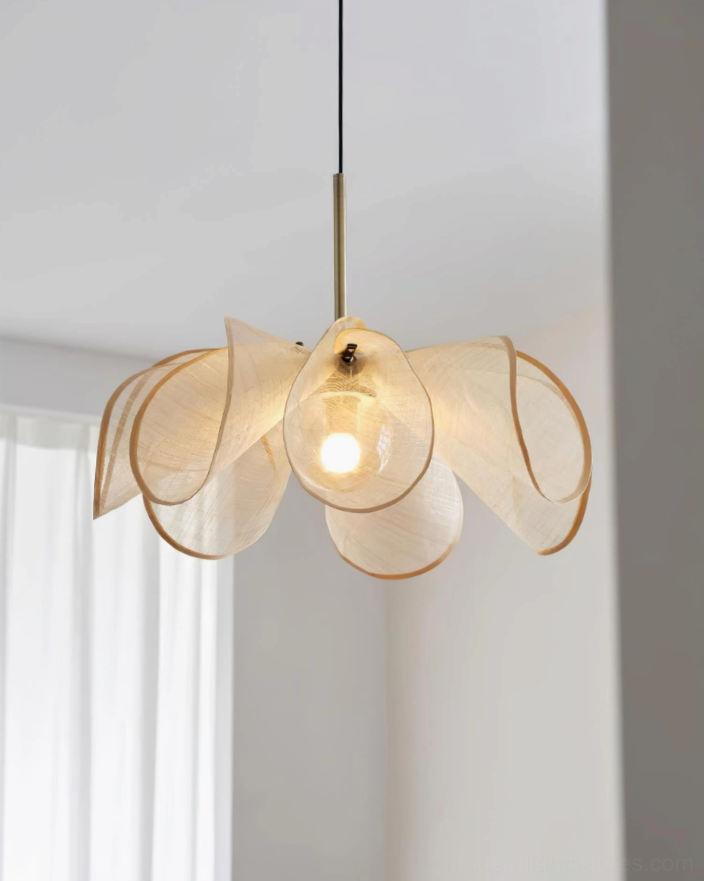 Beige jute flower petal pendant light in three-quarter view with sheer white curtain showing natural fabric weave and exposed bulb