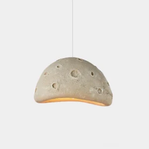 Meteorite crater pendant light in beige with textured dome surface and warm underglow, front low-angle view on white background