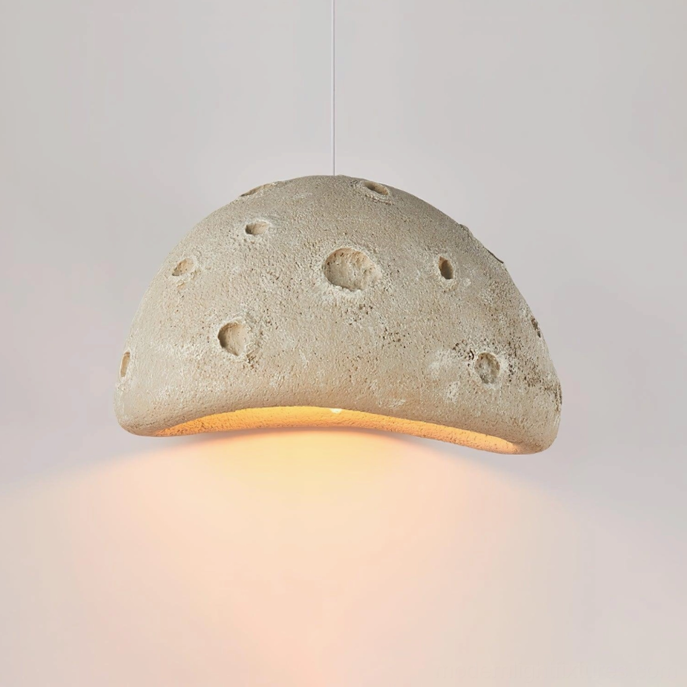 Beige meteorite crater pendant light suspended at optimal height showing downward warm illumination pattern