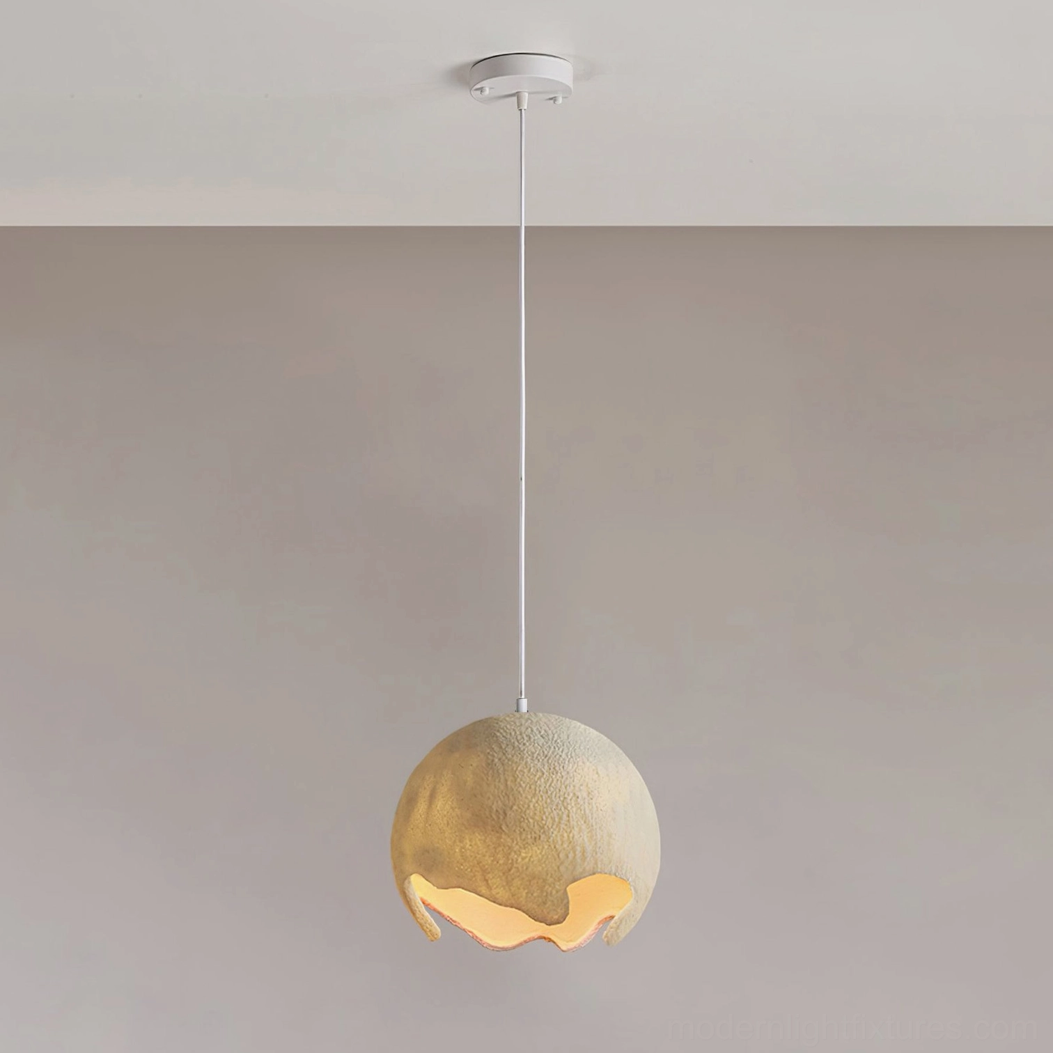 Beige milk coffee moon crater pendant light with small matte shade suspended from white ceiling, warm glowing bottom cutout
