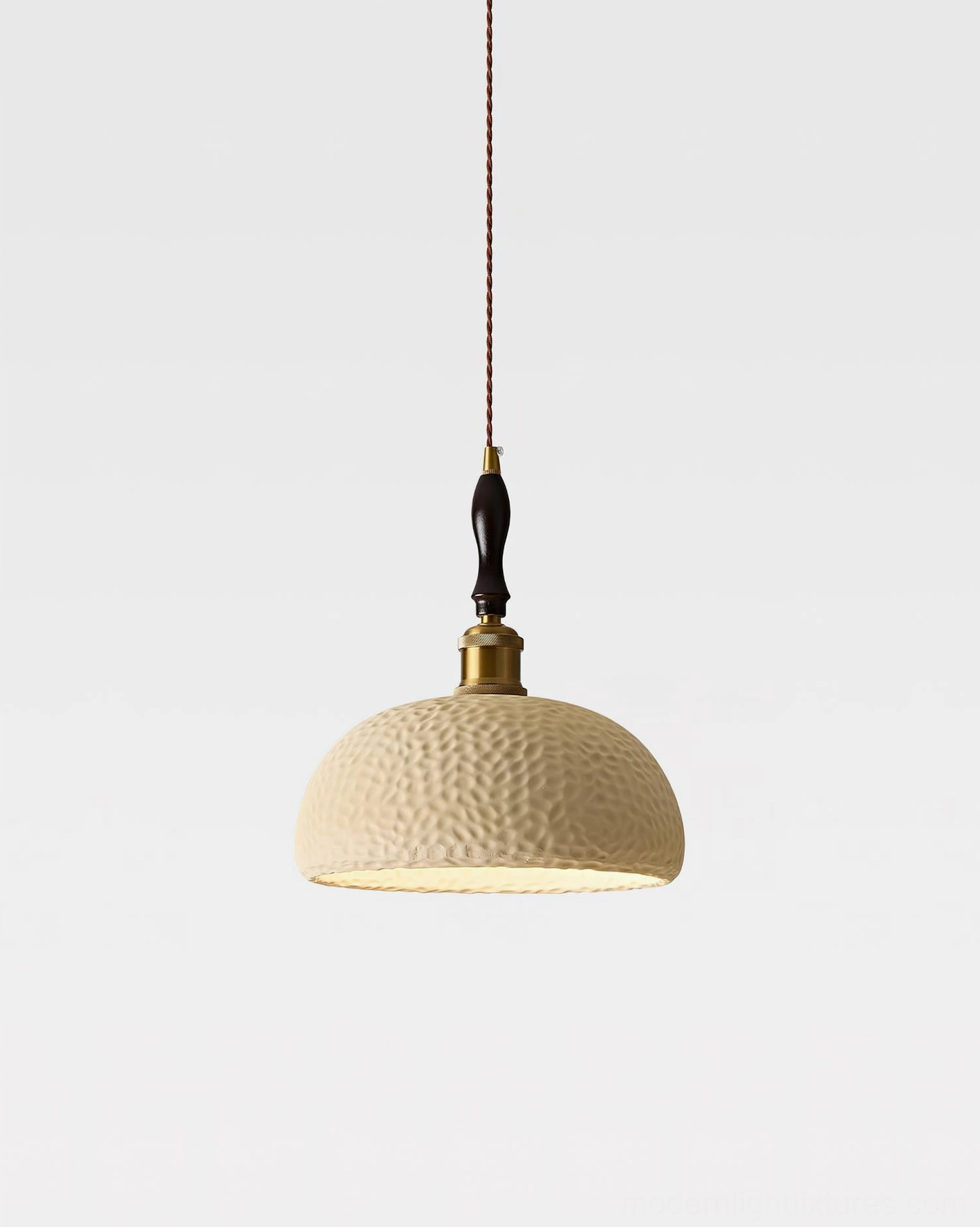 Beige textured resin dome pendant with brass suspension and wood neck detail, studio hanging view