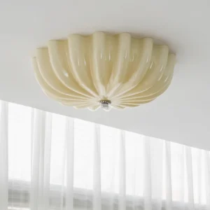 Beige jelly shell flush mount ceiling light installed in bedroom with sheer curtains, upward angled view showing scalloped glass diffuser