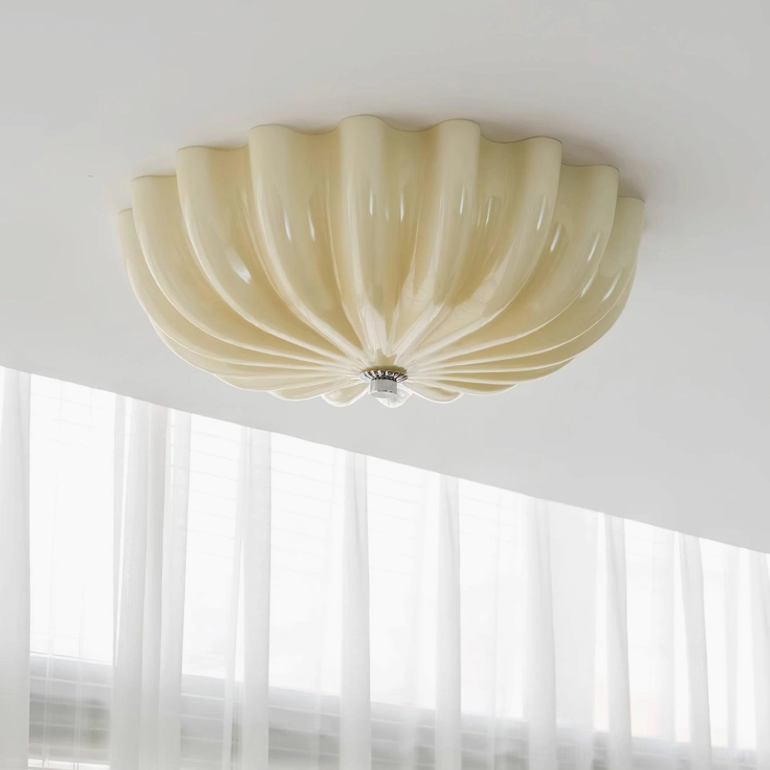 Beige jelly shell flush mount ceiling light installed in bedroom with sheer curtains, upward angled view showing scalloped glass diffuser