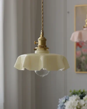 Beige ruffled glass pendant lamp with brass gold hardware hanging in cozy home interior with warm ambient lighting
