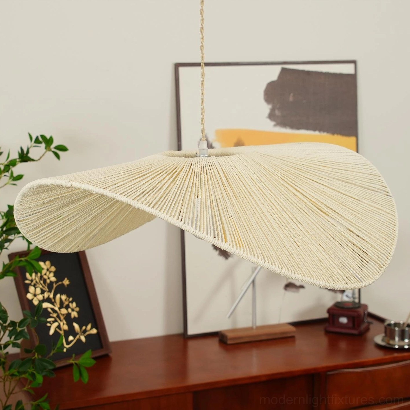 Beige woven straw hat pendant light fixture suspended in bright modern dining area with natural light