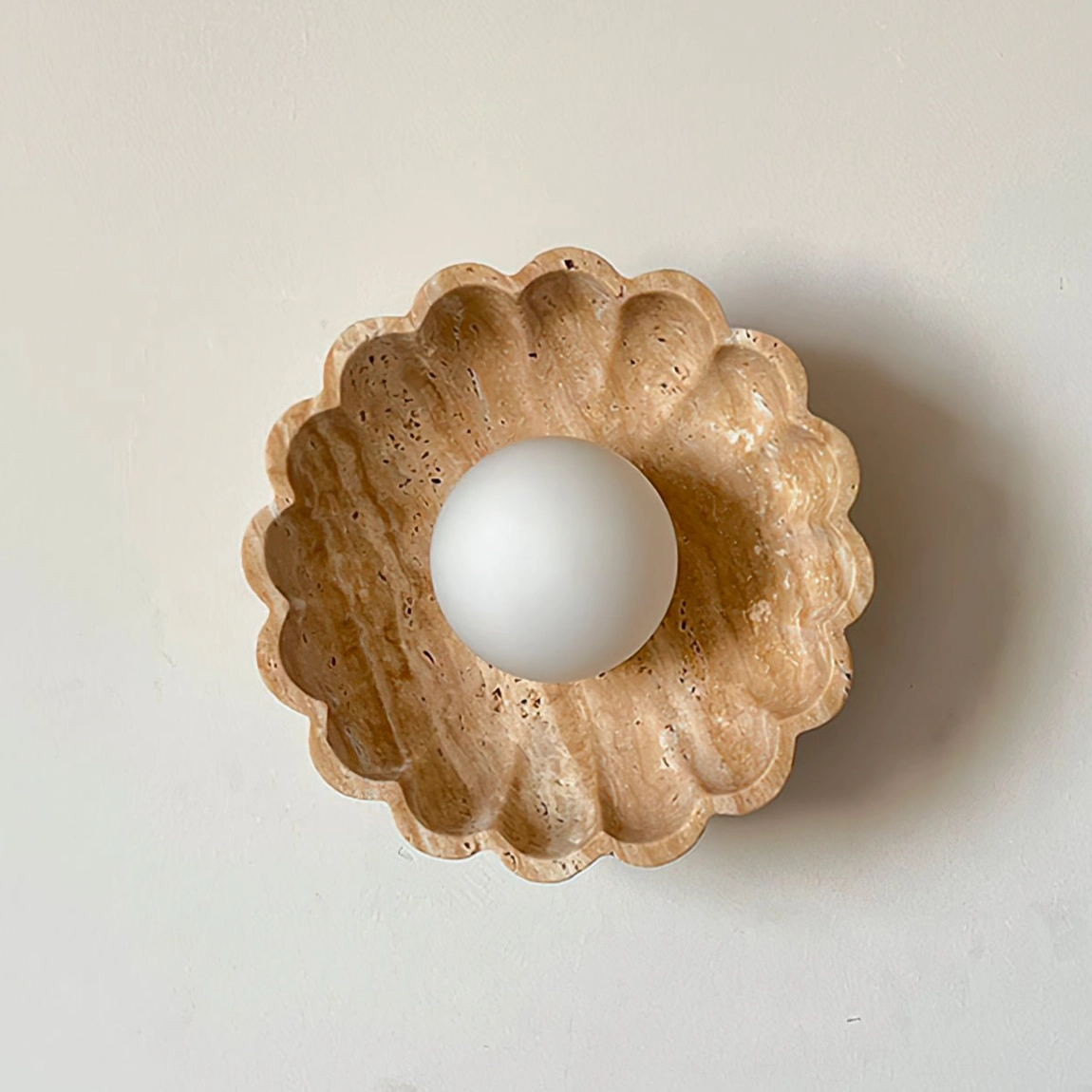 Beige travertine scallop wall sconce with frosted glass diffuser - close-up detail of natural stone texture