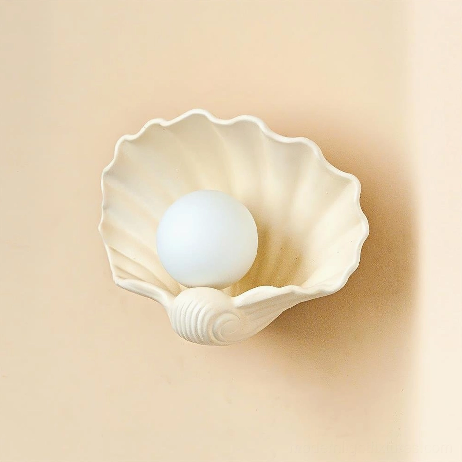 Beige and white ceramic scallop wall sconce, two-tone sculptural design, warm matte finish coastal fixture