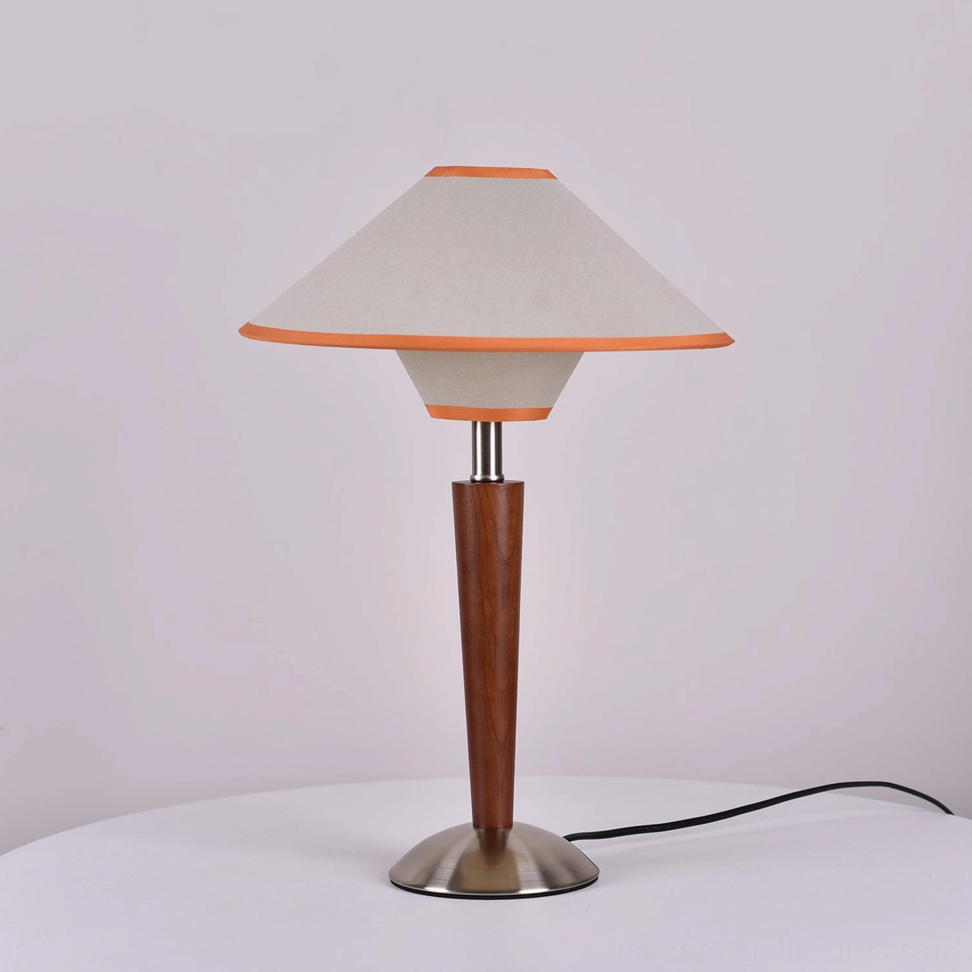 Beige white fabric table lamp with orange trim and wooden pole on minimalist white tabletop background