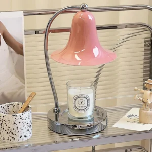 Modern bell candle warmer lamp displayed on industrial shelf with pink glass shade and decorative accessories