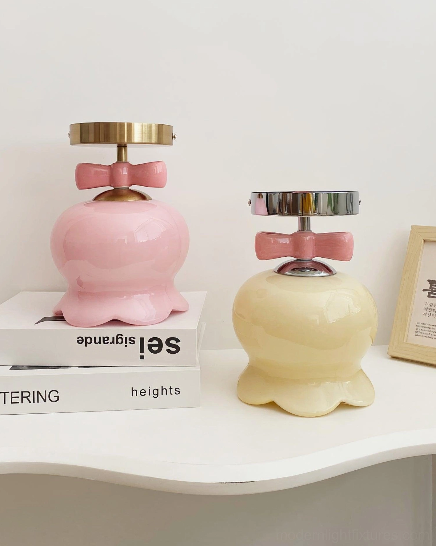 Tabletop display of two bell ceiling light variants: pink brass-base and cream chrome-base styles on decorative shelf