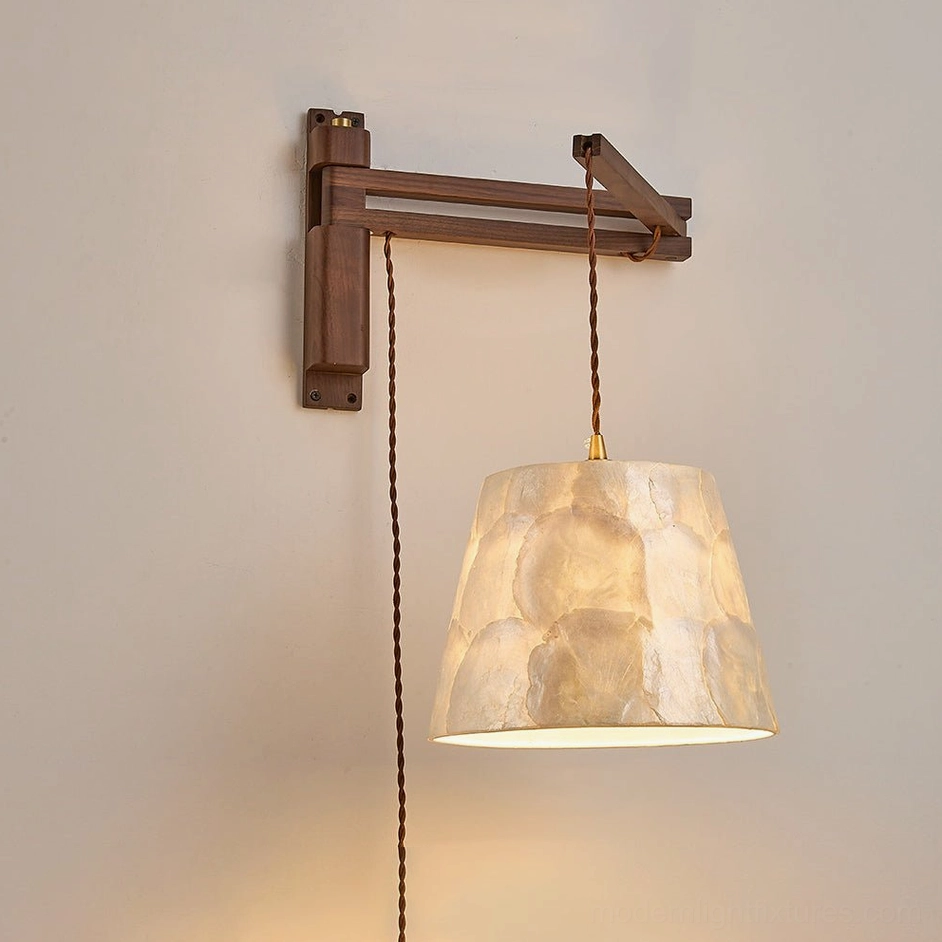 Walnut swing-arm wall sconce in bell shade silhouette, mounted in interior bedroom or living room setting