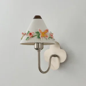 Bellafleur wall sconce three-quarter angle showing cream pleated ceramic shade, brass arm, and 5-petal flower-shaped ash wood backplate