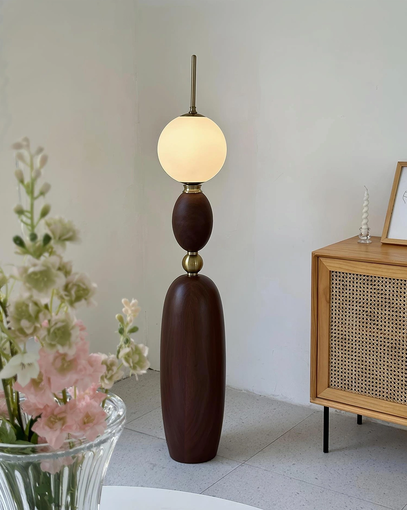 Warm walnut Bellamy floor lamp in bright living room with natural decor and rattan furniture