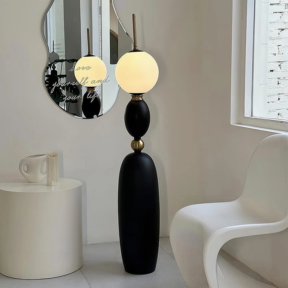 Sleek matte black Bellamy floor lamp in lounge area with round mirror and warm ambient lighting