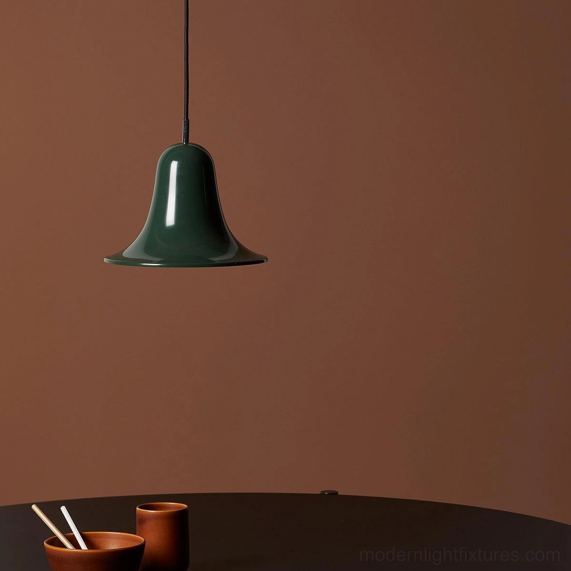Dark green Bells pendant light in minimalist dining corner setting, contemporary interior design application, tableware styling
