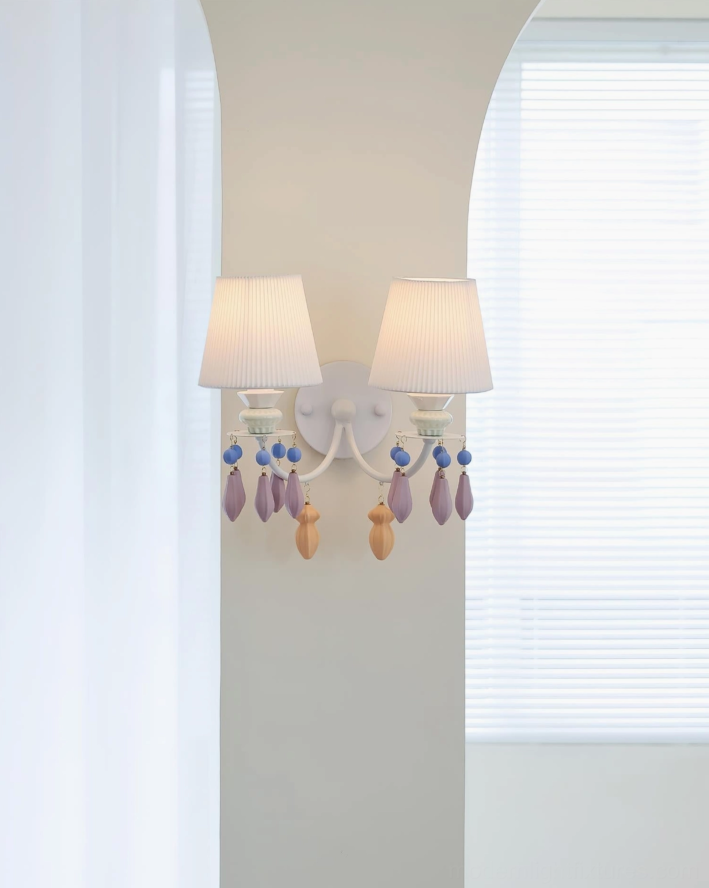 Belvianne double-head wall sconce installed on archway wall in indoor residential space with pleated shades and beaded accents
