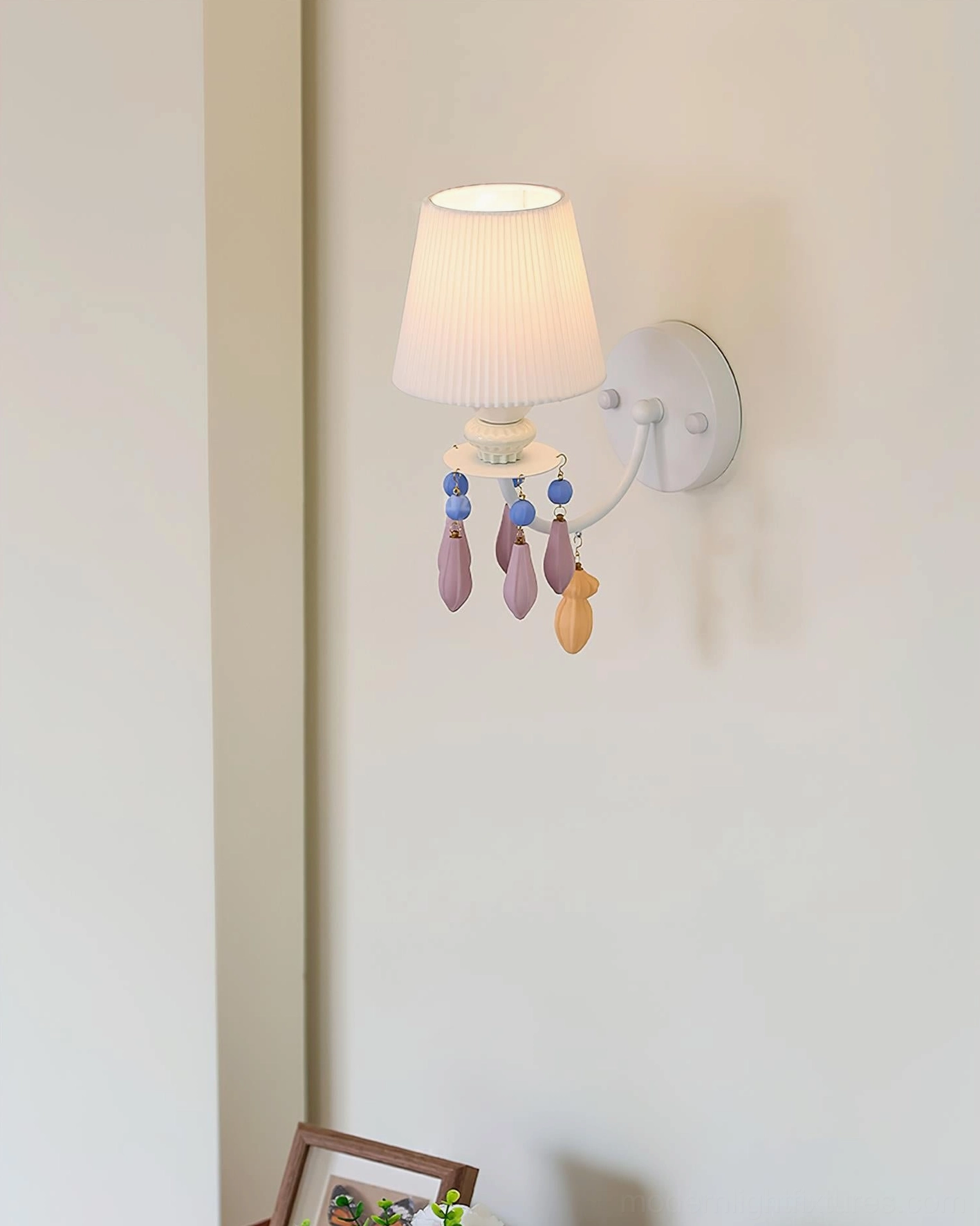 Belvianne single-head ceramic wall sconce mounted on residential corner wall with framed artwork and colorful hanging ornaments
