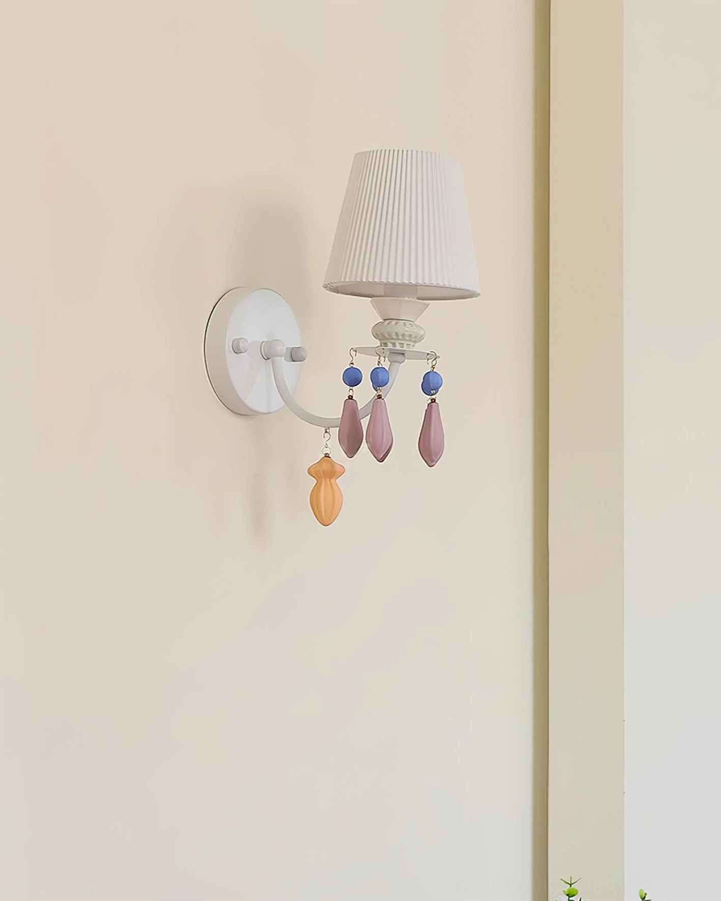 Belvianne single-head wall sconce side view showing off-white pleated ceramic shade and minimal pastel pendant decorations