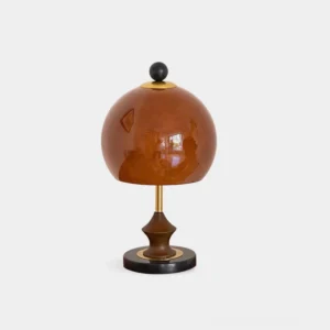 Bent table lamp with brown spherical glass shade and black marble base, studio front view
