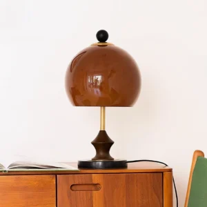 Mid-century bent table lamp in walnut and amber finish displayed on wooden cabinet